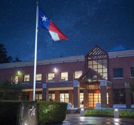 night view of a campus building and Texas flag